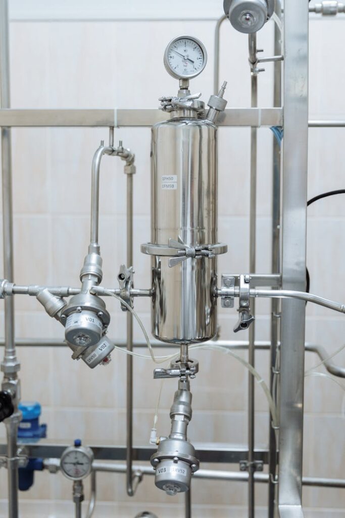 Close-up of a stainless steel industrial plumbing system with pressure gauges and steel pipes.